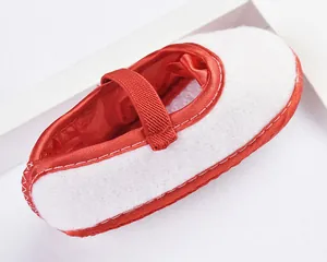 Nahaufnahme von weißem Baby-Mädchen-Prinzessinnenschuh mit rotem Riemen