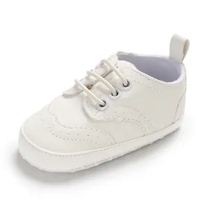 Zijaanzicht van witte baby loopschoentjes met klassieke wingtip stiksels en zachte zolen.