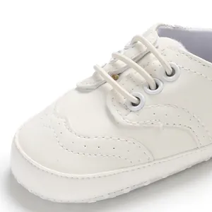 Macrodetail van witte zachte babyschoentjes voor de eerste stapjes met brogue-stiksels.