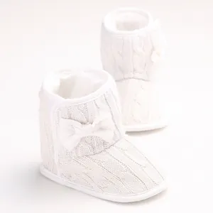 Detailansicht weißer Strick-Babystiefel für den Winter mit hübscher Schleife und Zopfmuster
