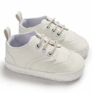 Zijaanzicht van witte baby loopschoentjes met zachte zool en elegante perforaties.