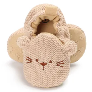 Nahaufnahme der beige gestrickten Babyschuhe mit süßem Katzenstickerei-Detail