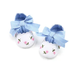 Detailed top view of white embroidered baby princess shoes with blue striped bows