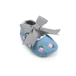 Close-up of blue baby walking shoe with pink flower embroidery and striped bow.