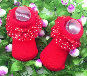 Detail von roten Baby-Prinzessinensocken mit Spitzenrüschen und gepunkteten Schleifen.