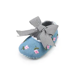 Close-up of baby girl walking shoe with pink flower embroidery and a striped bow