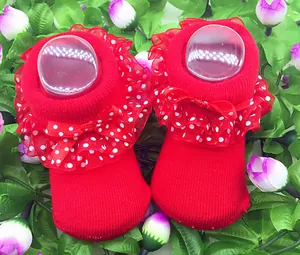 Süße rote Babysocken mit weißen gepunkteten Rüschen und einer zarten Schleife.