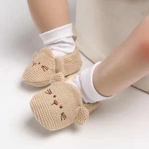 Detaillierte Nahaufnahme von süßen beige gestrickten Babyschuhen mit Katzengesicht