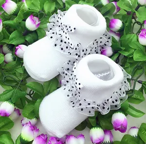 Detailansicht von weißen Babysocken mit eleganter Rüschenspitze und gepunkteter Schleife