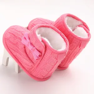 Nahaufnahme von rosa gestrickten Babystiefeln mit weichem weißem Kunstfellfutter und Schleife.