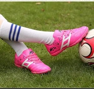 Close-up of pink children soccer shoes with white stripes on green grass field