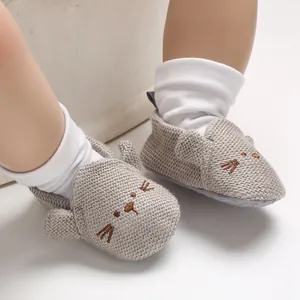 Detail der grauen gestrickten Babyschuhe mit niedlichem Tiergesicht und Ohren