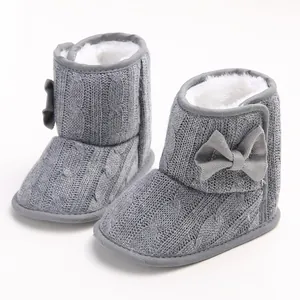 Nahaufnahme graue gestrickte Babystiefel mit Schleife und weichem Kunstfell
