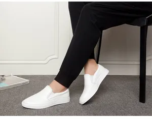 Men's white leather slip-on loafers shown on a model for a stylish casual look.