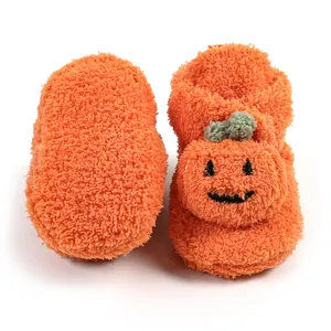 Primo piano di scarpine da neonato a forma di zucca di Halloween arancioni e soffici