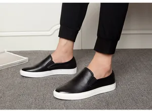 Close-up view of men's black leather slip-on loafers with white soles worn by a model