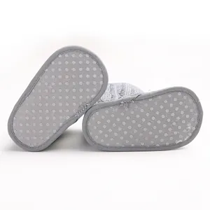 Detail der rutschfesten Sohlen an grauen weichen gestrickten Baby-Lernlaufschuhen