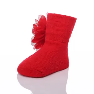 Nahaufnahme einer roten Neugeborenen-Baumwollsocke mit großer Chiffon-Blume.