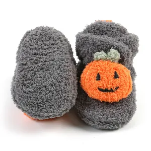 Primo piano di pantofole grigie per neonati con un simpatico design a zucca di Halloween