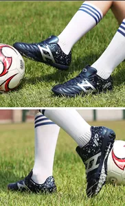 Detail view of children's turf soccer shoes in navy blue on grass field