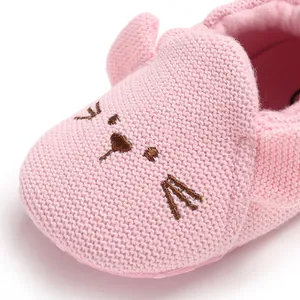 Nahaufnahme der rosa gestrickten Baby-Lauflernschuhe mit süßem Stickerei-Gesicht