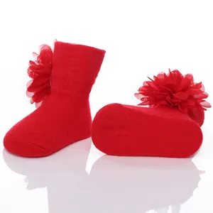 Detail der roten Baby-Baumwollsocken mit elegantem großem Chiffon-Blumendekor