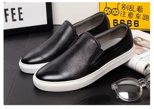 Detailed view of premium black pebble-grain leather slip-on loafers with white soles.