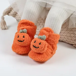 Dettaglio di morbide scarpine neonato a zucca arancione per Halloween e il calore autunnale.