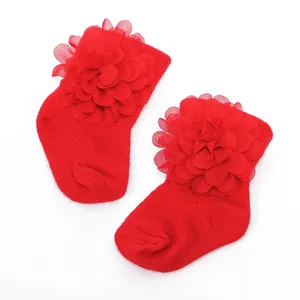 Detailaufnahme roter Baumwollsocken für Neugeborene mit großer Chiffonblume