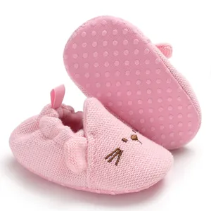Detailansicht von rosa gestrickten Baby-Lauflernschuhen mit Katzenstickerei und rutschfester Sohle.