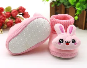 Detail of pink plush infant booties featuring a 3D rabbit face and anti-slip sole.