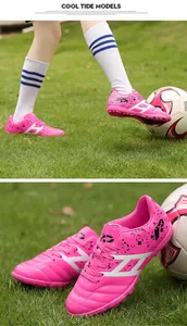 Bright pink children's soccer shoes with professional TF turf spikes on grass