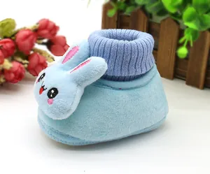 Close-up view of light blue plush baby booties featuring a cute 3D cartoon rabbit design.