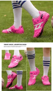 Detailed macro view of vibrant pink kids turf soccer shoes on a lush green grass field