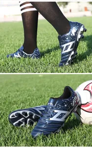 Detail view of blue children soccer cleats with silver splash pattern on turf field