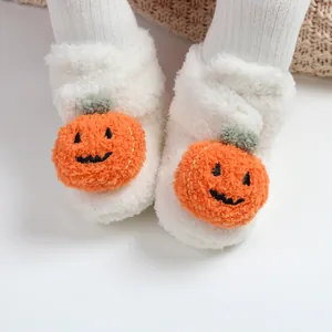 Dettaglio di scarpine neonato in morbido peluche bianco con decorazione zucca Halloween