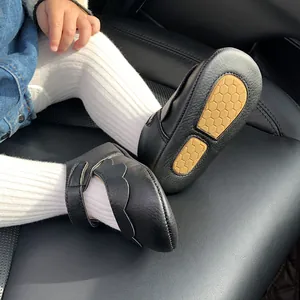 Detailed view of black PU leather baby shoes with soft anti-slip soles worn by a child