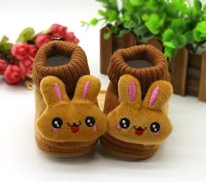 Close-up of plush baby shoes with 3D bunny faces and knitted ribbed cuffs for winter.