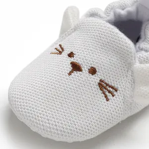 Nahaufnahme eines weiß gestrickten Baby-Lauflernschuhs mit süßem Katzen-Stickereimuster