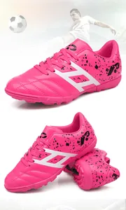 Detail view showing vibrant pink kids soccer shoes with unique black splatter pattern