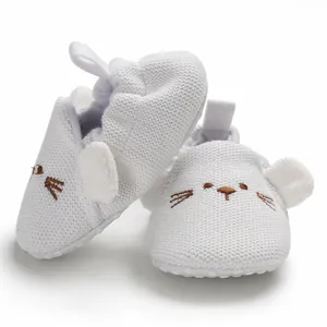 Nahaufnahme weißer Strick-Babyschuhe für Lauflerner mit gesticktem Tiergesicht