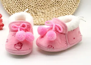 Dettaglio di scarpe primi passi in peluche rosa per neonati con pom-pom