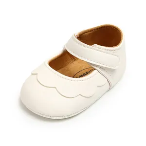 Detail view of white baby Mary Jane leather shoes with scalloped edges and velcro strap
