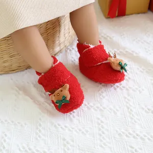 Nahaufnahme rote Fleece-Weihnachtsschuhe für Babys mit Rentier- und Schleifendetails