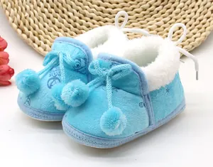 Primo piano di scarpine invernali in peluche blu per neonati con calda fodera e pompon