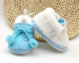 Dettaglio di stivaletti invernali in peluche bianco e blu per neonati con suola morbida