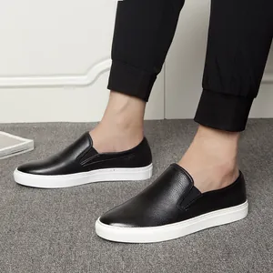 Men's premium black leather slip-on loafers with white rubber soles on a grey carpet.