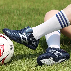 Boys professional turf soccer shoes with durable cleats displayed on green grass