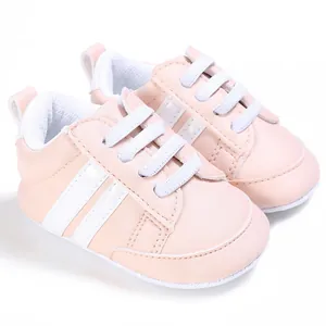 Vista detallada de zapatos rosas para bebés con suelas blandas y franjas blancas laterales