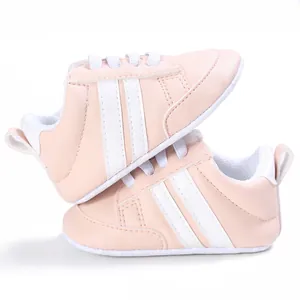 Detalle de zapatos rosas para primeros pasos con suela blanda y diseño de rayas blancas